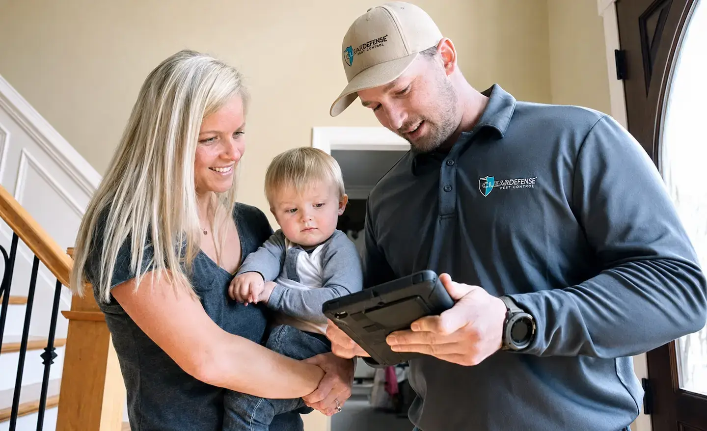 Young family with toddler consulting with security professional in branded polo and cap
